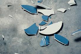A blue ceramic plate broken on the floor.